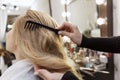 A blonde woman is combing her hair in a professional beauty salon. Beauty and care. Close-up. Back view Royalty Free Stock Photo
