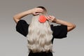 Blonde woman combs her gorgeous hair on a gray background. Back view