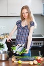 Blonde woman cooking lubina fish in frying pan Royalty Free Stock Photo