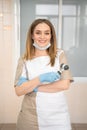 Blonde woman dermatologist with dermatoscope in uniform and gloves in doctor office, examination room in clinic