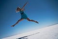 Blonde woman dressed in blue jumping a giant leap on a salt lake Royalty Free Stock Photo