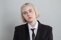 Blonde woman dressed in suit and tie poses on white background Royalty Free Stock Photo