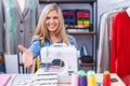 Blonde woman dressmaker designer using sew machine smiling friendly offering handshake as greeting and welcoming Royalty Free Stock Photo