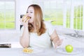 Blonde woman eating burger in kitchen Royalty Free Stock Photo