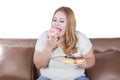 Blonde woman eats donuts on sofa Royalty Free Stock Photo