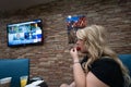 A blonde woman eats her free hotel breakfast watching fake news on Cable TV