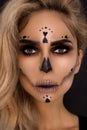 Blonde woman in Halloween makeup and leather outfit on a black background in the studio. Skeleton, monster and witch. Royalty Free Stock Photo