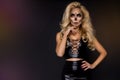 Blonde woman in Halloween makeup and leather outfit on a black background in the studio. Skeleton, monster and witch. Royalty Free Stock Photo