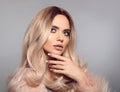 Blonde woman in glamorous fur coat posing in studio. Ombre blond hairstyle. Beauty fashion girl portrait. Beautiful model with Royalty Free Stock Photo