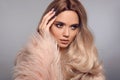 Blonde woman in glamorous fur coat posing in studio. Ombre blond hairstyle. Beauty fashion girl portrait. Beautiful model with Royalty Free Stock Photo