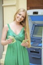 Blonde woman in a green dress is holding a cash dollars