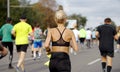 Blonde woman with hair bun running marathon on city road