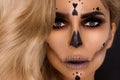 Blonde woman in Halloween makeup and leather outfit on a black background in the studio. Skeleton, monster and witch. Royalty Free Stock Photo