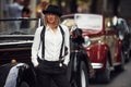 Blonde woman in hat and in black retro clothes near old vintage classic car Royalty Free Stock Photo