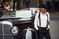 Blonde woman in hat and in black retro clothes near old vintage classic car Royalty Free Stock Photo