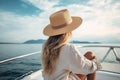 blonde woman with hat sits on a yacht and enjoys the summer holiday over the tropical ocean, AI Generated Royalty Free Stock Photo