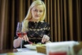 Blonde woman having dinner in a restaurant and pleasing with a glass of wine