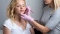 Blonde woman having permanent make-up tattoo on her eyebrows. Closeup beautician doing tattooing eyebrow.Professional makeup and Royalty Free Stock Photo