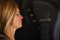 Blonde woman holding electric guitar, black background