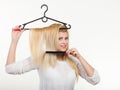 Blonde woman holding hair on clothes hanger