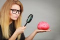 Woman holding magnifying glass investigating brain