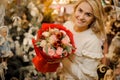 Blonde woman holds beautiful bouquet of fresh roses wrapped in red paper. Royalty Free Stock Photo