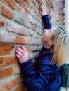 blonde woman intent on trying to climb a brick wall