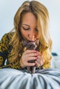 A blonde woman kissing the top of a Devon rex cat head. Pet concept. Vertical. Royalty Free Stock Photo