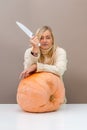 Woman with a knife is going to grind a huge pumpkin, the concept of preparing autumn vegetables Royalty Free Stock Photo