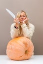 Woman with a knife is going to grind a huge pumpkin, the concept of preparing autumn vegetables Royalty Free Stock Photo