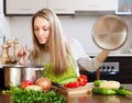 Blonde woman with ladle testing soup from pan