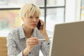 Blonde woman listens to client talking on phone at workplace