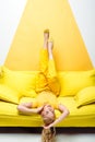 Blonde woman lying upside down on sofa on white and yellow Royalty Free Stock Photo