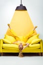 Blonde woman lying upside down on sofa on white and yellow Royalty Free Stock Photo