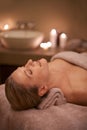 Blonde woman, massage therapy and candlelight for wellness, smile and relaxation to destress and pamper. Female person