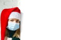 Blonde woman in medical face mask peeking from behind blank sign billboard assign white brick wall. gnome girl, copy Royalty Free Stock Photo