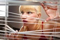 Blonde woman observes through blinds