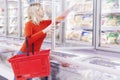 A blonde woman in an orange sweater chooses frozen foods in a supermarket Royalty Free Stock Photo