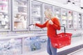 A blonde woman in an orange sweater chooses frozen foods in a supermarket. Blurred Royalty Free Stock Photo