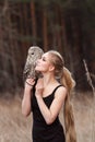 Blonde woman with an owl in her hands walks in the woods in autumn and spring. Long hair girl, romantic portrait with owl. Art Royalty Free Stock Photo