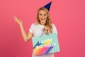 blonde woman in party hat holding Happy Birthday bag, studio Royalty Free Stock Photo