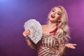 Blonde woman with a perfect hairstyle and bright make-up is posing with fan of hundred dollar bills in her hands. Casino Royalty Free Stock Photo