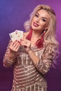 Blonde woman with a perfect hairstyle and bright make-up is posing with playing cards in her hands. Casino, poker. Royalty Free Stock Photo