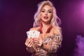 Blonde woman with a perfect hairstyle and bright make-up is posing with playing cards in her hands. Casino, poker. Royalty Free Stock Photo