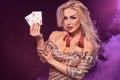 Blonde woman with a perfect hairstyle and bright make-up is posing with playing cards in her hands. Casino, poker. Royalty Free Stock Photo