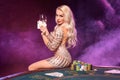 Blonde woman with a perfect hairstyle and bright make-up is posing with playing cards in her hands. Casino, poker.