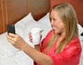 Blonde woman on phone holding coffee wearing robe Royalty Free Stock Photo
