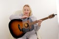 blonde woman playing classical guitar relaxed with serious expression on face Sad hug guitar in home playing classical Royalty Free Stock Photo