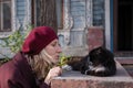 Blonde woman plays with a cat on the porch of an country house