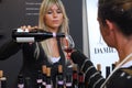 Blonde woman pouring red wine from the bottle to the glass of customer